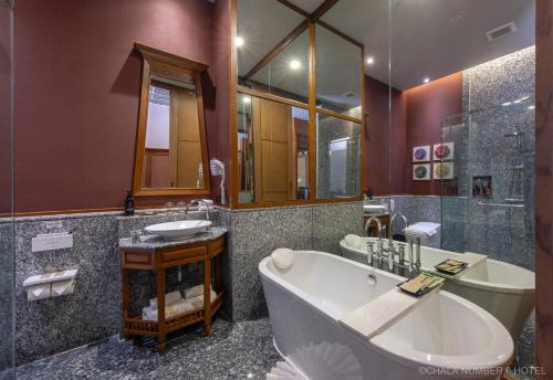 a bathroom with a tub and a sink and a mirror at Chala Number6 in Chiang Mai