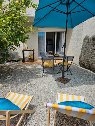a patio with two chairs and a table with an umbrella at Studio calme avec jardin in Canet-en-Roussillon
