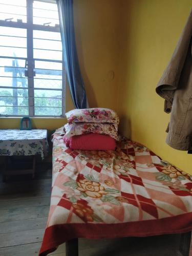 a bed with a quilt on it in a room at Avi Homestay in Kohīma