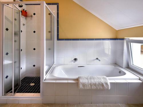 a white bathroom with a tub and a shower at Auberge La Dauphine Guest House in Franschhoek