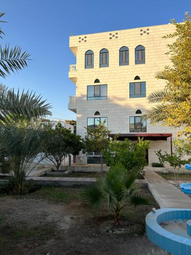 a tall yellow building with trees in front of it at Valley Guest Home in Nizwa