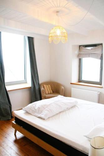 une chambre avec un lit, une chaise et des fenêtres dans l'établissement La Romance,vue mer, jardin et proche plage, à Roscoff