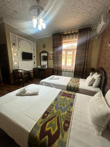 a hotel room with two beds and a television at Sharq Plaza in Bukhara