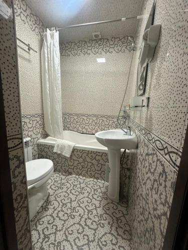 a bathroom with a sink and a toilet and a tub at Sharq Plaza in Bukhara