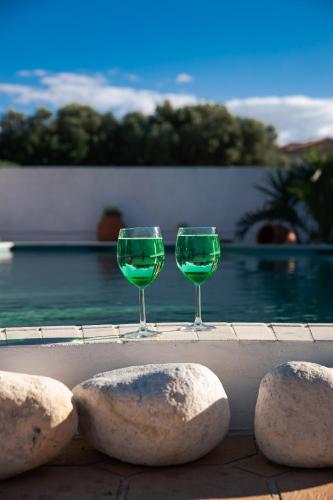 two glasses of green wine sitting next to some rocks at Lagonisi Luxury Escape in Lagonissi