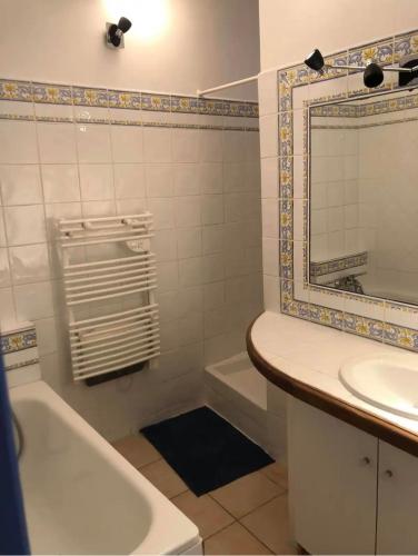 een badkamer met een bad, een wastafel en een spiegel bij La maison de vacances in Lauris