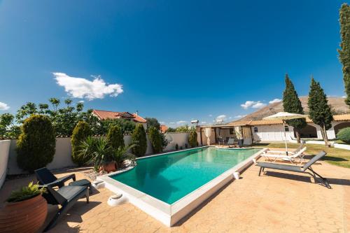 a swimming pool in a yard with chairs and a house at Lagonisi Luxury Escape in Lagonissi