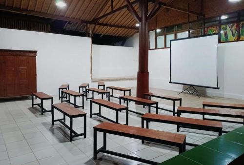 a classroom with wooden benches and a screen at Bamboo Sanctuary Pancawati in Ciherangsating