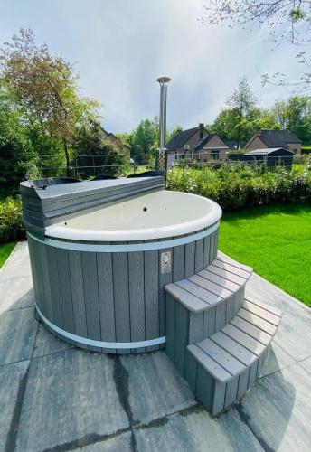 a jacuzzi tub with two stairs in a yard at 6pers Boshuis -Hottub Jacuzzi- 'De Groene Specht' in Ewijk