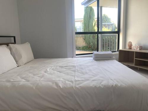 a white bed in a room with a large window at Beautiful Mountain Views in Kings Meadows