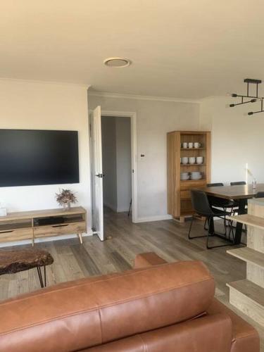 a living room with a couch and a television on a wall at Beautiful Mountain Views in Kings Meadows