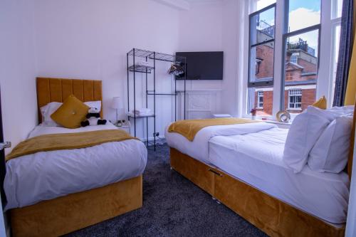 two beds in a room with a window at Oxford Street Grandeur - Perfect for Large Groups in London