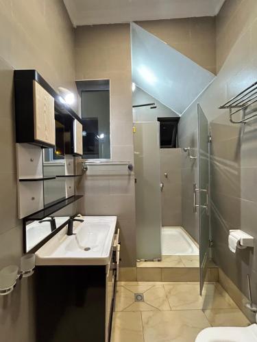 a bathroom with a sink and a shower and a toilet at Explore Iwacu Stay in Kigali