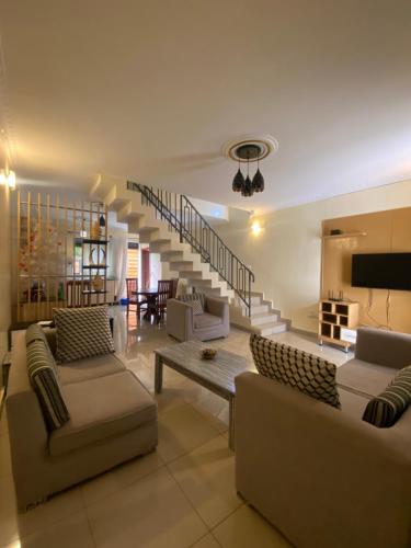 a living room with two couches and a staircase at Explore Iwacu Stay in Kigali