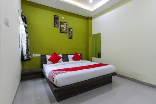 a green bedroom with a bed with red pillows at OYO Nabhyansh Elite in Indore