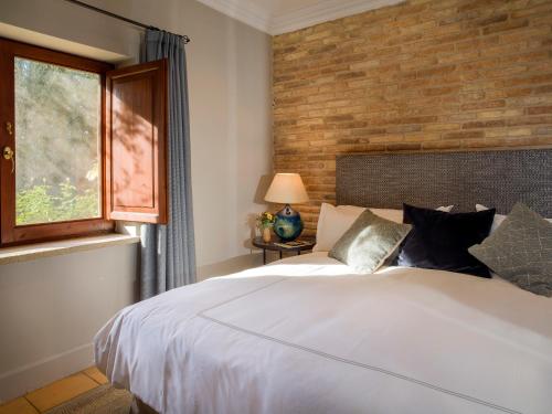 ein Schlafzimmer mit einem weißen Bett und einer Ziegelwand in der Unterkunft La Torre del Visco - Relais & Châteaux in Fuentespalda