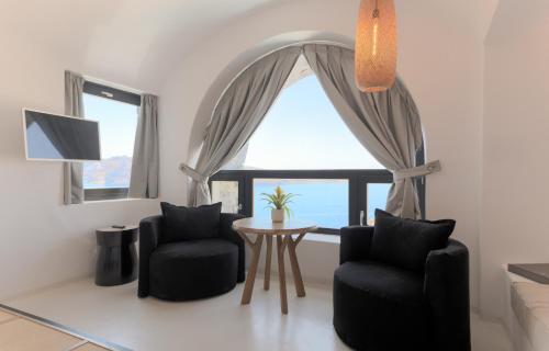 a living room with two chairs and a table and a window at Charisma Suites in Oia