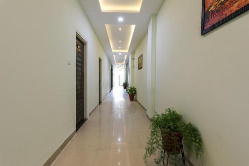 a hallway with white walls and a hallway with plants at OYO Nabhyansh Elite in Indore