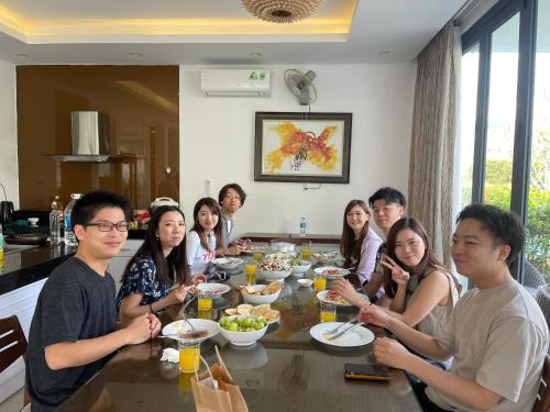 a group of people sitting around a table eating food at Astana Villa Non Nuoc Beach in Da Nang