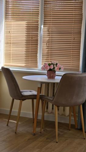 a table with two chairs and a vase of flowers on it at Studio Anna in Panevėžys