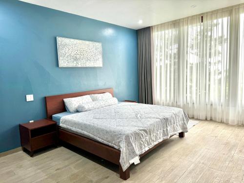 une chambre avec un lit et un mur bleu dans l'établissement Mattina Villa, à Hạ Long