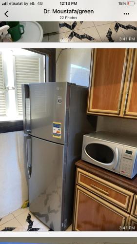 eine Küche mit einem Kühlschrank aus Edelstahl und einer Mikrowelle in der Unterkunft الميرغني مصر الجديده in El-Alamein