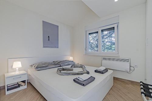 a white bedroom with a bed and a window at Vila Inga - Postira in Postira