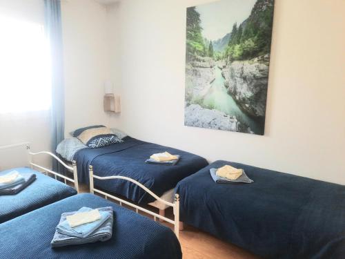 three beds in a room with a painting on the wall at GITE CHEZ MONETTE in Nance