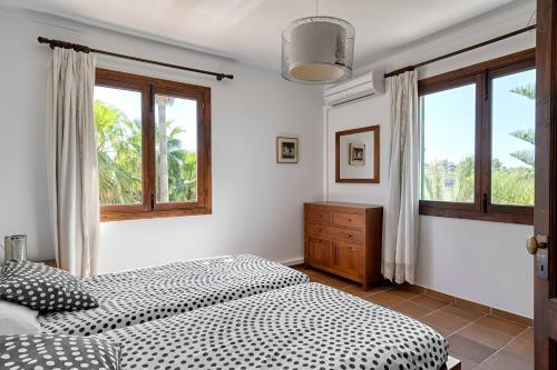 a bedroom with a bed and two windows at Finca Sa Punta in Santa Margalida