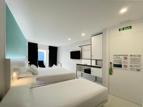 a hotel room with two beds and a tv at Four Rooms in Muxia