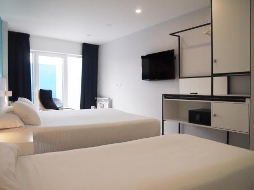 ムシアにあるFour Roomsのベッド2台とテレビが備わるホテルルームです。