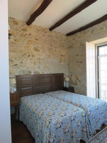 ein Schlafzimmer mit einem Bett und einer Steinmauer in der Unterkunft Casa Pita Caminha in Caminha