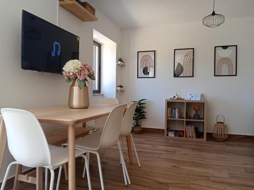a dining room table with white chairs and a vase of flowers at Casa Raios de Sol in Burgau