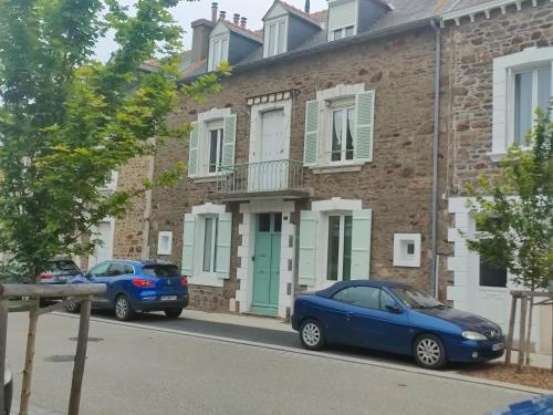deux voitures garées devant un bâtiment en briques dans l'établissement STUDIO MEUBLE DINARD RDC DROITE, à Dinard