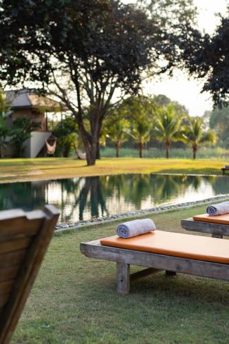 two towels sitting on a bench in front of a pond at Khla Lodge in Kampot