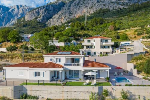 a large white house with a mountain in the background at Villa Mira Mel mit privaten Pool - Makarska Exklusiv in Makarska