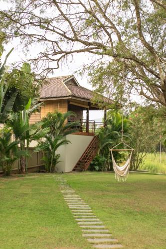 a house with a hammock in front of a yard at Khla Lodge in Kampot