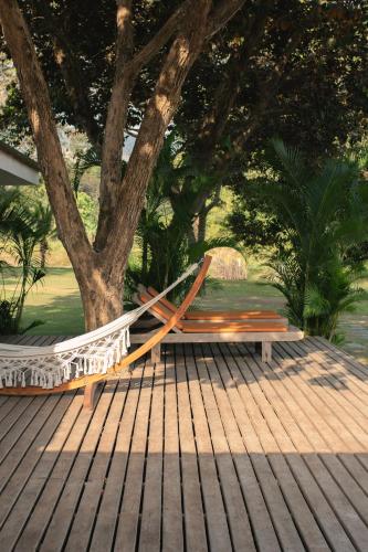 a hammock on a deck next to a tree at Khla Lodge in Kampot