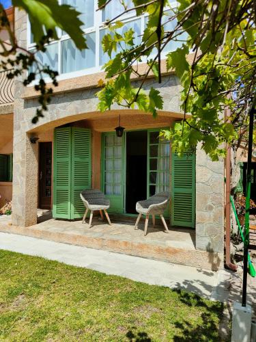 2 chaises assises sur la terrasse couverte avant d'un bâtiment dans l'établissement Maison de campagne piscine et jardin privatifs près de la plage, à Aléria