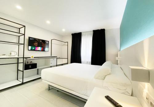 1 dormitorio con 1 cama blanca y TV en Four Rooms, en Muxía
