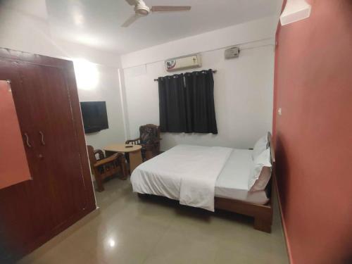 カスホールナガーにあるShanthana holiday inn coorgのベッドルーム1室(ベッド1台、椅子、テーブル付)