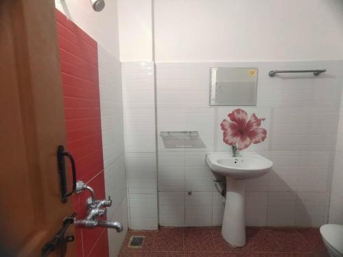 un baño con lavabo y una flor rosa. en Shanthana holiday inn coorg en Kushālnagar