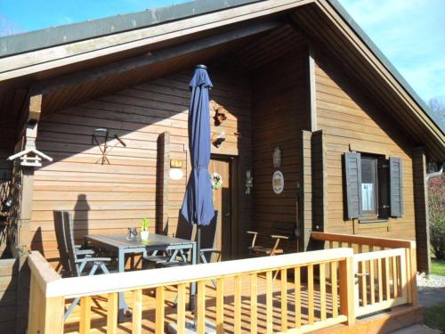 a wooden cabin with a table and an umbrella at Komfortables-Ferienblockhaus-Nr-27-56-qm-bis-4-Personen-Viechtach-Jaegerpark in Viechtach