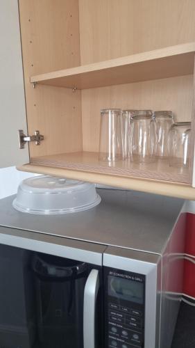 a kitchen with a microwave and some dishes on a shelf at Fair Oak Self-Catering Accomodation in Sandown
