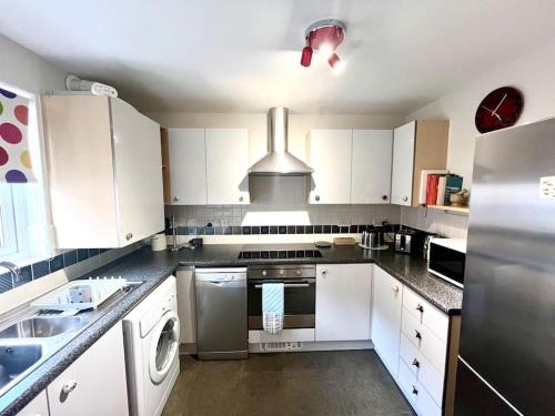 a kitchen with white cabinets and a stove top oven at TM - Modern 1 bed parking and garden in Stratford-upon-Avon