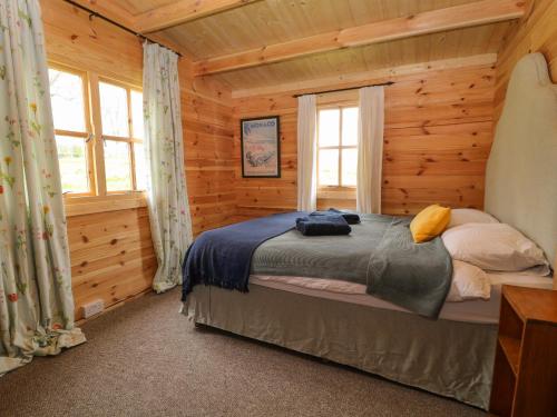 una camera con un letto in una baita di tronchi di Manor Farm Cabin 