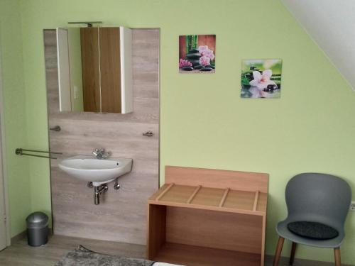 a bathroom with a sink and a mirror and a chair at Ferienwohnung Morretalblick in Buchen