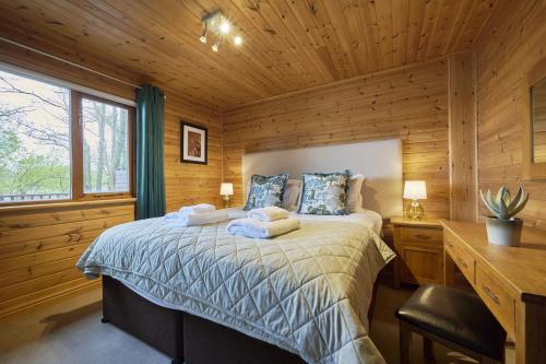 a bedroom with a bed in a wooden cabin at Fieldfare Lodge with Hot-tub in Carlisle