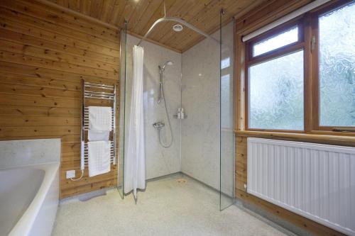 ein Bad mit einer Dusche, einer Badewanne und einem Fenster in der Unterkunft Fieldfare Lodge with Hot-tub in Carlisle