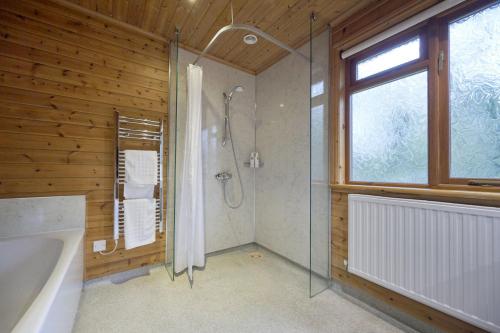 a bathroom with a shower and a tub and a window at Fieldfare Lodge with Hot-tub in Carlisle